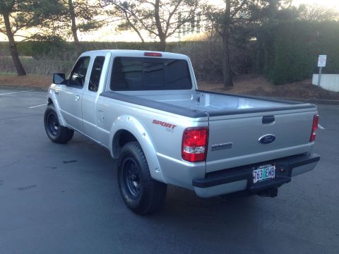 2010 Ford Ranger - This silver Ford Ranger pickup truck is shown from a rear three-quarter angle, with a 'Sport 4x4' decal visible on the fender.