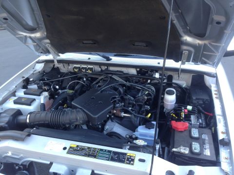 2010 Ford Ranger - The engine bay of a silver Ford Ranger shows its internal components under the open hood.