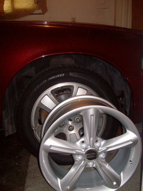 2004 Ford Crown Victoria - A shiny new wheel is presented in front of the vehicle it is intended for.