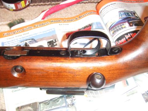 1996 Ford Bronco - A rifle's wooden stock and trigger mechanism are shown, with a catalog vehicle parts in the background.