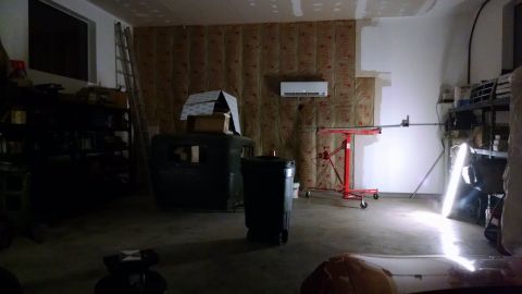 1995 Ford Bronco - A dark garage scene shows an old vehicle body with boxes stacked on top, next to a trash can.