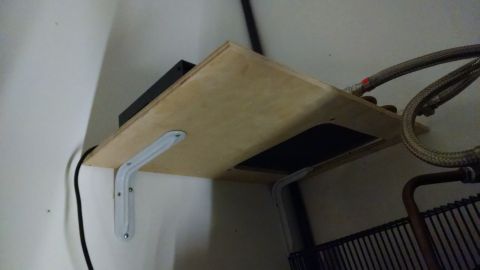 1995 Ford Bronco - A shelf holds an electronic device and is situated near plumbing connections and a black grate.