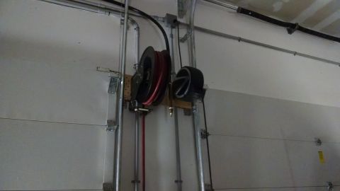 1995 Ford Bronco - A garage door mechanism is visible with an air hose reel and a tire mounted on the wall.