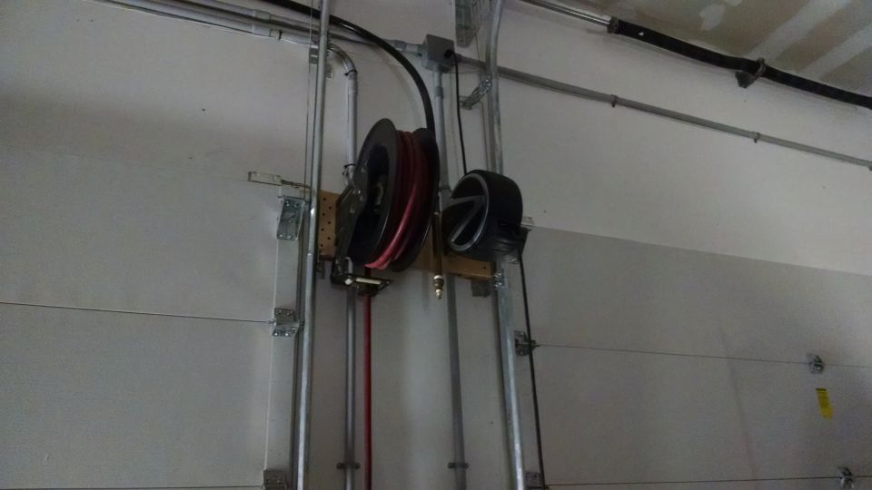 Garage door mechanism with air hose reel and tire mounted on wall