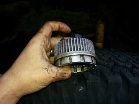 1981 Ford Bronco - A mechanic holds a Warn Hub part, likely for a 4x4 vehicle, in front of a tire.