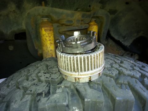 1981 Ford Bronco - A Warn Hub assembly rests on a tire, with parts of the vehicle's suspension visible in the background.