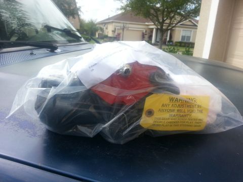 1994 Ford Bronco - A steering box part, still in its packaging, sits on a vehicle's hood. A yellow warning tag is attached.