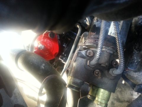 1994 Ford Bronco - Close-up view of a red steering box and related engine parts, with visible hoses and wiring.