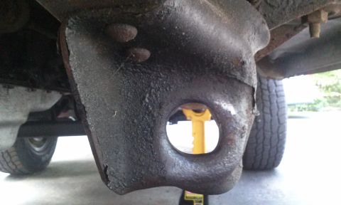 1994 Ford Bronco - This image shows a close-up view of a heavily rusted suspension component from the undercarriage of a vehicle.