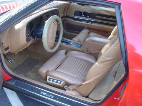 1980 Ford Mustang - The tan leather interior of a red car features plush seats and a detailed dashboard.