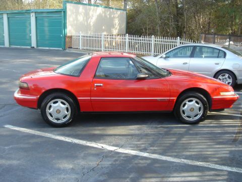 1980 Ford Mustang - Side view of a red Buick Reatta coupe parked in a lot next to a silver sedan.