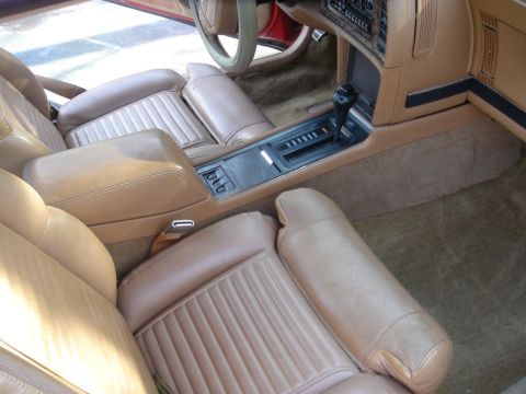 1980 Ford Mustang - Interior view of a car's tan leather seats and dashboard, showing the center console and shifter.