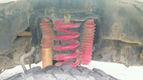 1990 Ford Bronco - Front suspension components, likely from a truck or SUV, showing red springs and shocks.
