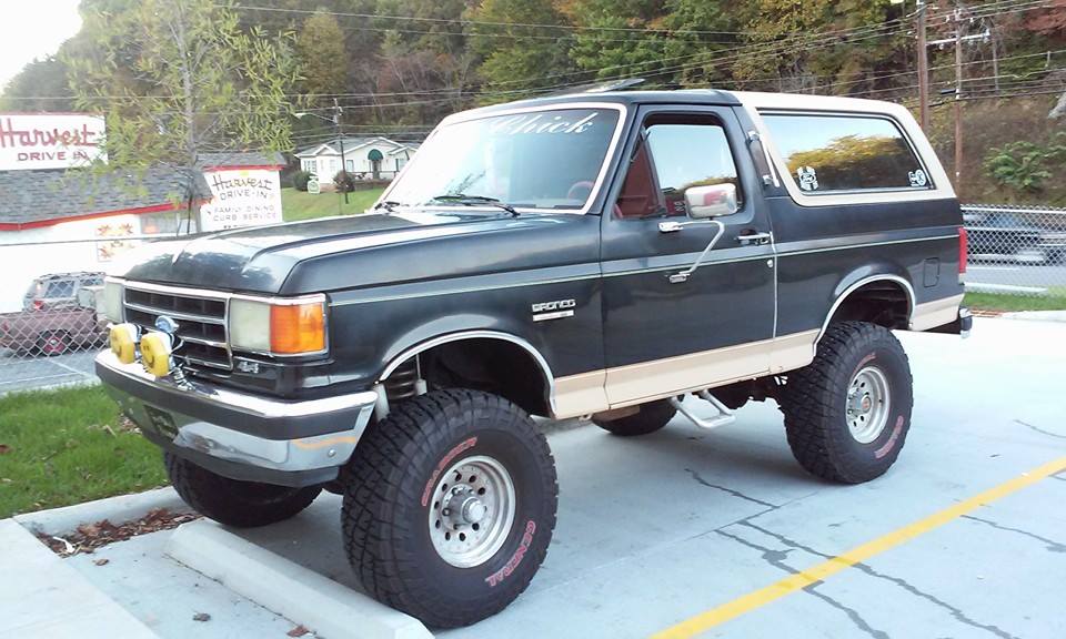 Dark green and tan lifted Ford Bronco with off-road tires parked in a lot
