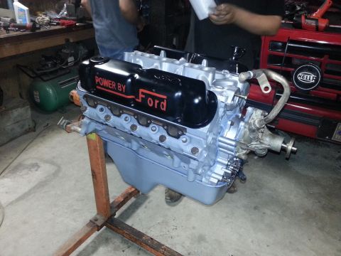 1995 Ford Bronco - A Ford V8 engine is displayed on a stand in a workshop setting, with "POWER BY Ford" visible on the valve covers.