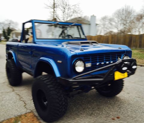 1974 Ford Bronco - This blue 1974 Ford Bronco features a custom front bumper and a hood scoop, giving it a appearance.