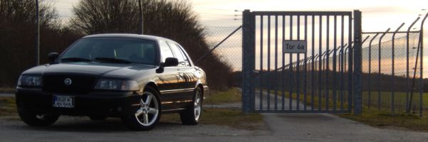 Black 2003 Mercury Marauder parked near a closed gate with 'Tor 6a' sign
