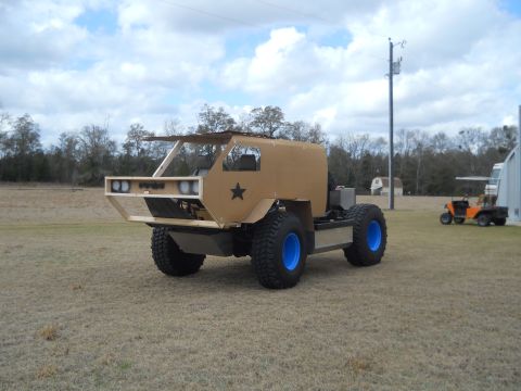 1992 Ford Bronco - A custom-built off-road vehicle with a unique tan body and bright blue wheels is parked in a grassy field.