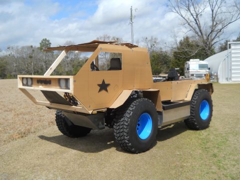 1992 Ford Bronco - A homemade vehicle with a cardboard exterior and blue wheels sits on a grassy field under a cloudy sky.