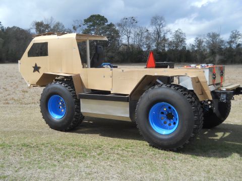 1992 Ford Bronco - This custom-built vehicle features large off-road tires with striking blue rims and an unfinished wooden body, suggesting a project in prog…