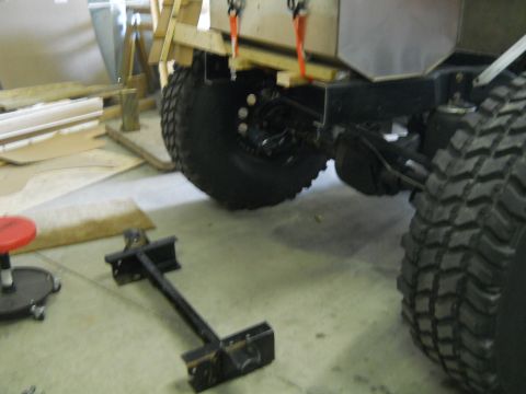 1992 Ford Bronco - Close-up view of the rear axle and tire of a vehicle being worked on in a garage, with wooden construction elements visible.