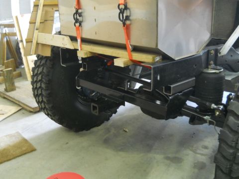 1992 Ford Bronco - A vehicle's frame and suspension are visible as a large crate is lowered onto it.