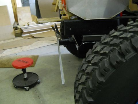1992 Ford Bronco - A large, knobby tire is prominent in the foreground, next to the chassis of a vehicle in what appears to be a workshop.