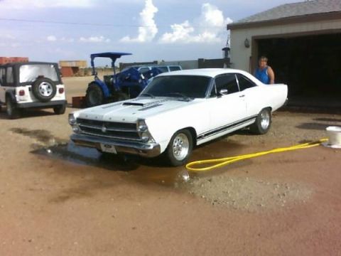 1966 Ford Fairlane - A white 1966 Ford Fairlane is parked outside a garage, with a yellow hose on the ground.