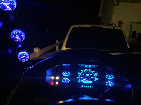 1995 Ford Bronco - Dashboard interior with multiple illuminated gauges and a steering wheel, at night.