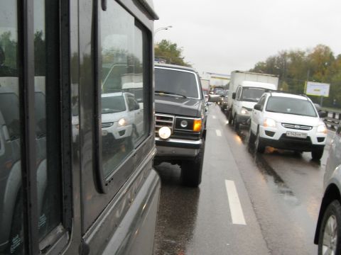 1987 Ford Bronco - A black 1987 Ford Bronco is seen in traffic on a wet road, alongside other vehicles.