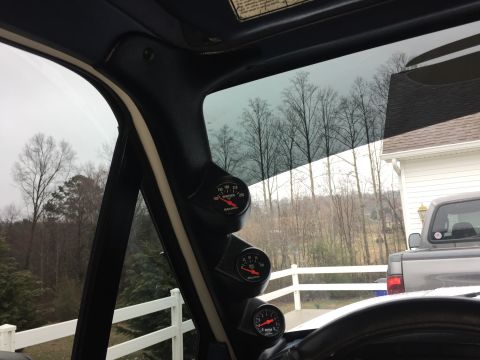 1995 Ford Bronco - A view from inside a vehicle shows a set of dashboard gauges, with a pickup truck visible through the window.