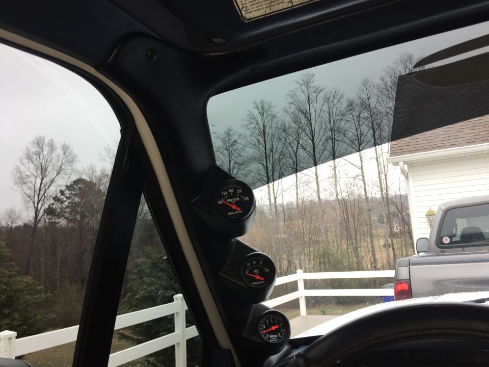 Interior view of dashboard gauges and a pickup truck outside