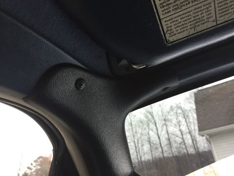 1995 Ford Bronco - Interior A-pillar and visor clip detail, with a visible warning label on the sun visor.