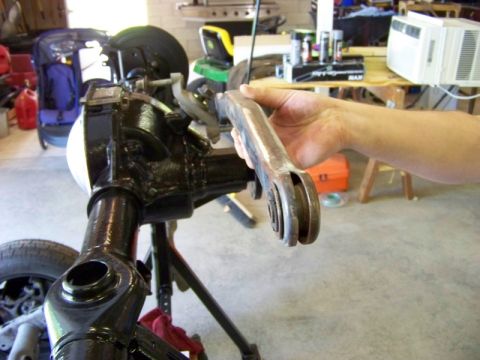 1999 Mercury Grand Marquis - A person is holding a car part near a rear axle assembly that is mounted on a stand in a garage.