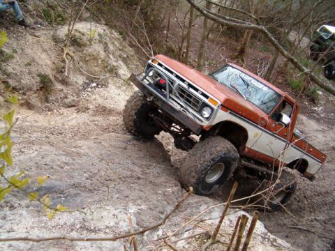 1991 Ford Bronco - A lifted Ford truck navigates an off-road trail with another vehicle visible in the background.