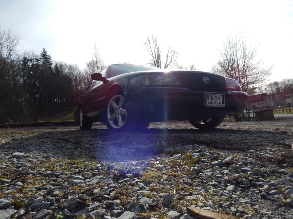 Black 2003 Mercury Marauder with chrome wheels, front view, parked on gravel