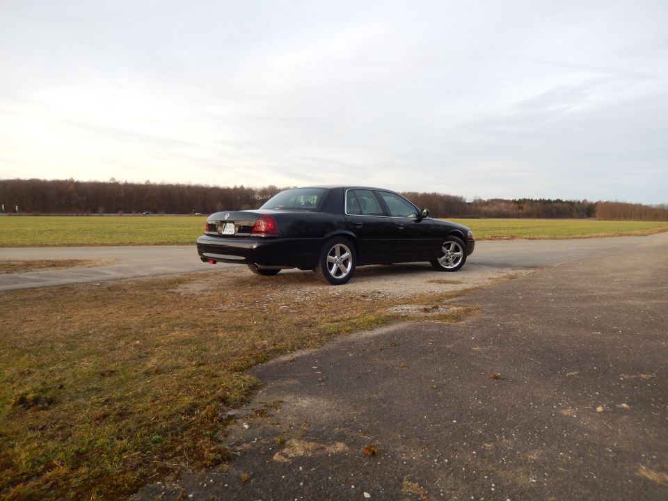 Black 2003 Mercury Marauder parked on a road next to a field