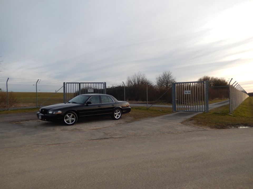 Black 2003 Mercury Marauder parked on asphalt near a chain-link fence and gate
