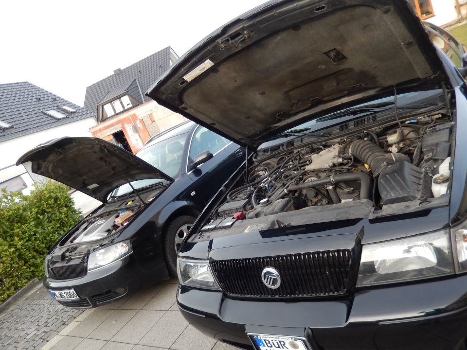 Front view of a black 2003 Mercury Marauder and a dark sedan, both with hoods open