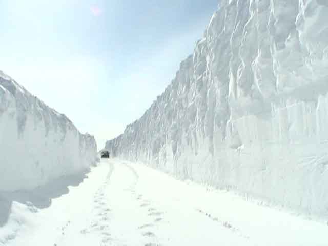 Vehicle driving on a road with very high snowbanks on either side