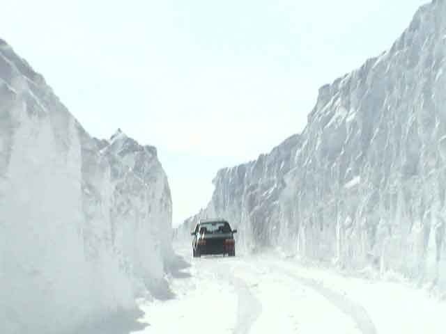 Car driving on a snow-covered road between tall snow walls