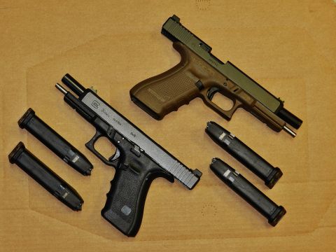 1996 Ford Bronco - Two handguns and their magazines are laid out on a textured brown surface.