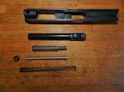 1996 Ford Bronco - Disassembled components of a firearm are arranged on a wooden background.