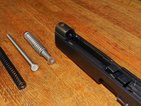 1996 Ford Bronco - Disassembled firearm components rest on a wooden table.