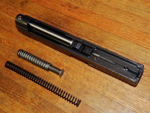 1996 Ford Bronco - Disassembled gun slide and recoil springs laid out on a wooden surface. The Supermotors.net logo is visible in the lower right corner.