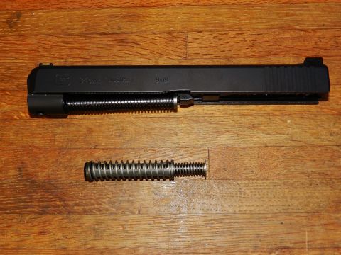 1996 Ford Bronco - Glock slide and recoil spring assembly shown separately on a wooden background.