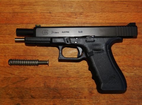 1996 Ford Bronco - A Glock 34 Gen 4 pistol and its recoil spring are shown disassembled on a wooden table.
