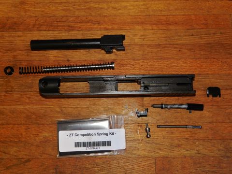 1996 Ford Bronco - Various handgun components, including a slide, barrel, and a competition spring kit, are laid out on a wooden surface.