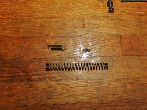1996 Ford Bronco - Three metal springs are shown on a wooden surface, possibly for repair or replacement.