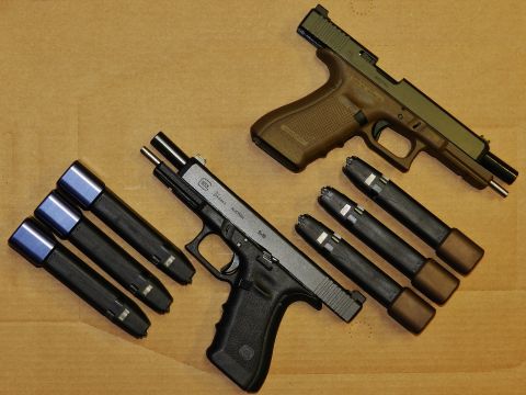1996 Ford Bronco - Two handguns and multiple magazines are laid out on a textured surface, with a website logo visible in the corner.